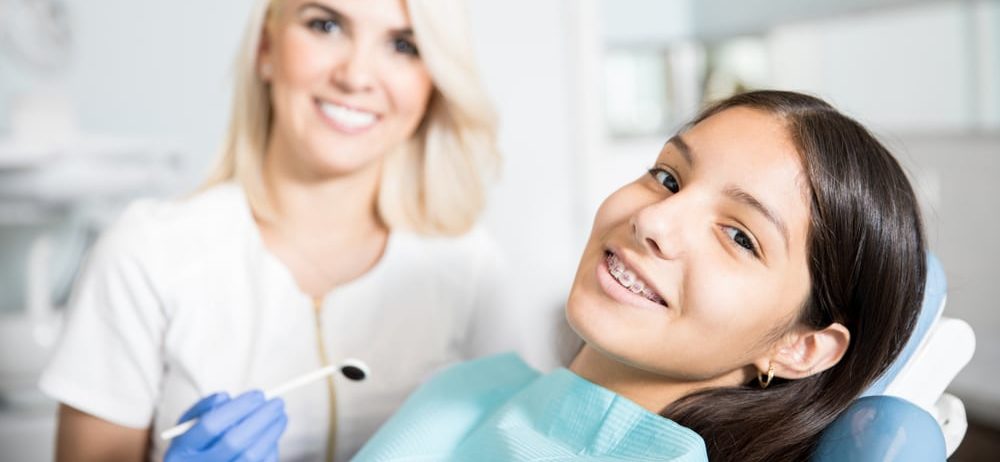 an orthodontic assistant inspecting a young girls braces