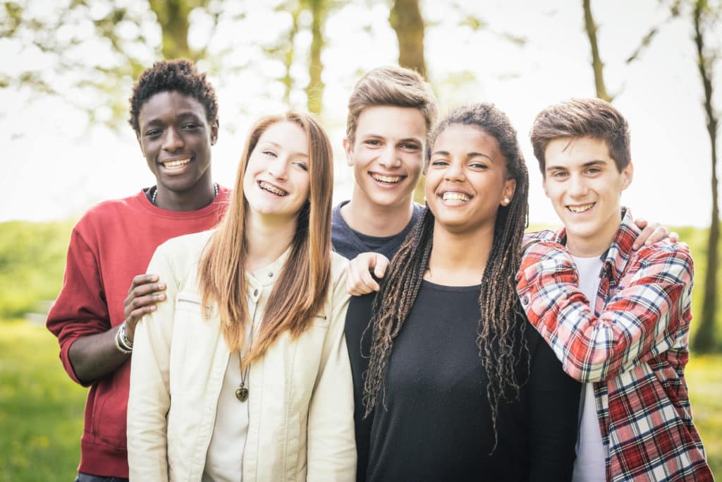 a group of young people smiling and standing next to each other