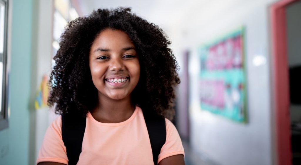 a young girl smiling with braces while she standing in the middle of the hall