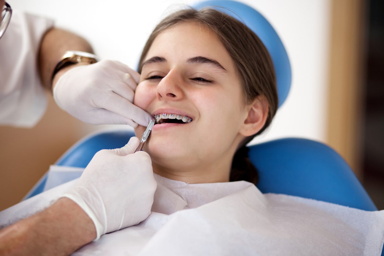 a young girl getting her braces checked by an orthodontist