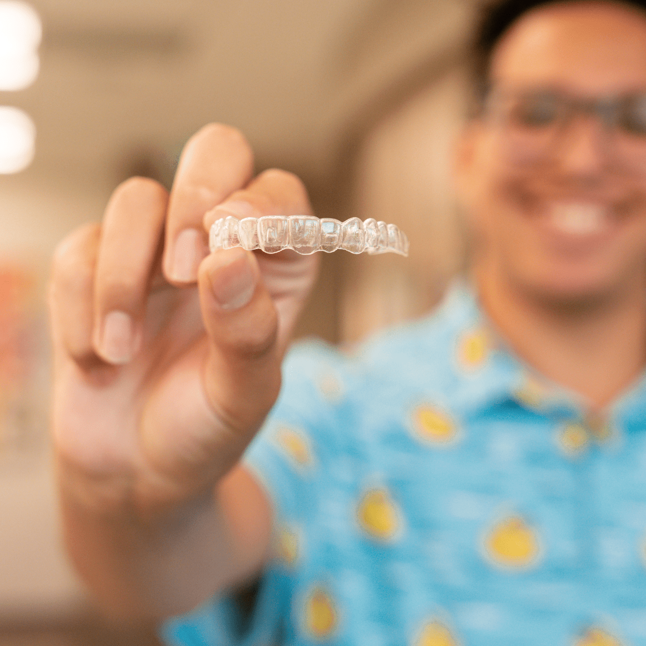Patient holding clear aligners at a Fresno orthodontist office