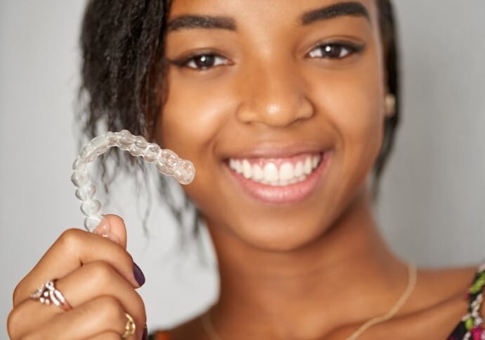 Close-up shot of a smiling girl holding medical invisible braces